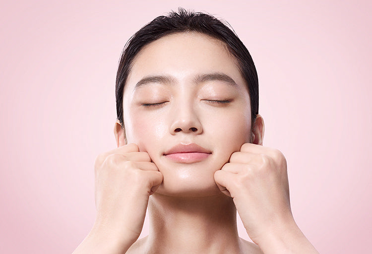 SUQQU Gankin Massage™ model portrait peforming massage step with hands on her lower cheeks.