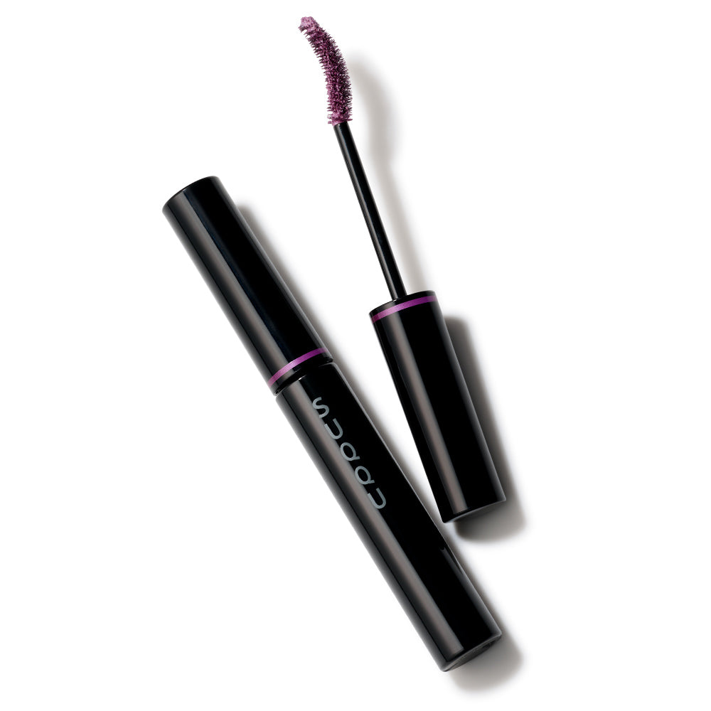 A black SUQQU Nuance Mascara 101 Amethyst Purpl shade mascara tube with the cap removed, showing the applicator wand and a glittery mauve-pink shade on a white background. The tube has a purple band and vertical 'SUQQU' branding.