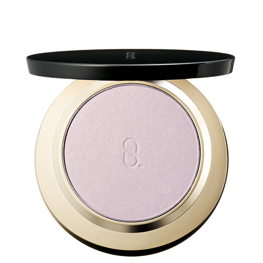 An open round SUQQU Glow Setting Powder e 101 face powder makeup compact with a black lid resting above the compact, showing a shimmering light lavender-pink pressed powder in a metallic gold case on a white background.
